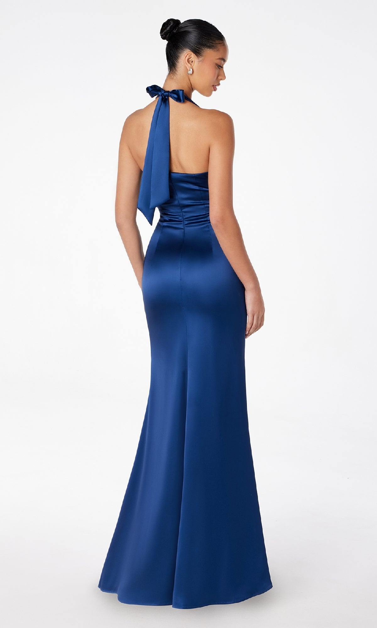 A woman models the Astee T2001 Bow-Back Long Satin Halter Prom Dress in royal blue, featuring a floor-length empire waist and back bow detail, set against a plain white background.